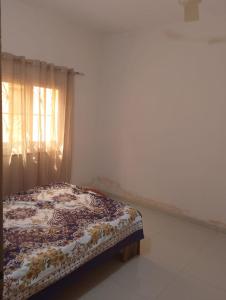 un lit assis dans une pièce avec une fenêtre dans l'établissement La maison de Kalabancoura, à Bamako