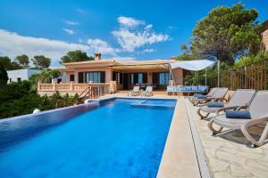 a swimming pool with chairs and a house at Ses Penyes in Santanyi