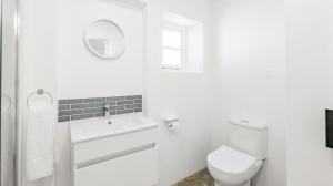 a white bathroom with a toilet and a sink at 30 Beach Drive Langezandt Struisbaai in Struisbaai