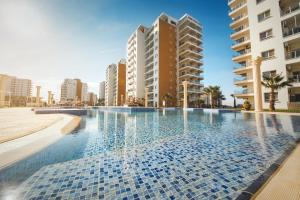 a swimming pool in front of some tall buildings at Ground Garden & Pool View Spacious Apartment at Caesar Resort & SPA in Famagusta