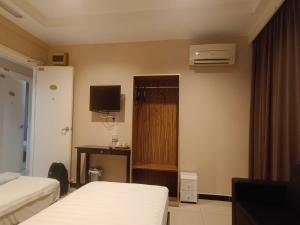 a hotel room with two beds and a television at Hotel O Rainfield Inn in Kota Kinabalu