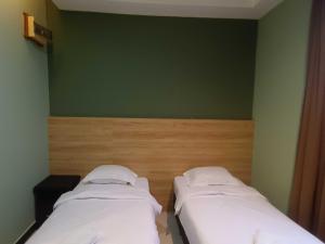two beds in a room with a green wall at Hotel O Rainfield Inn in Kota Kinabalu