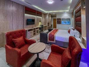 a hotel room with a bed and two chairs and a table at Ceedapeg Hotels in Uyo