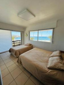 two beds in a room with a view of the beach at La Casona el Encanto in El Quisco