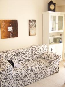 a couch in a living room with a clock on the wall at Eirini Apartment in Nea Kalikratia