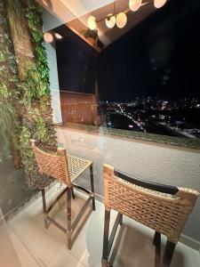 two wicker chairs sitting in front of a window at Um sonho de apartamento! Piscina maravilhosa! in Sorocaba +11 photos