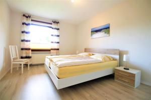 ein Schlafzimmer mit einem Bett und einem Stuhl und einem Fenster in der Unterkunft Ferienwohnung Kube in Grömitz + 14 Fotos