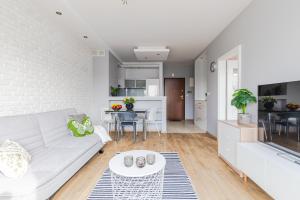 Una sala de estar con un sofá blanco y una mesa. en Apartament Kiedacza, darmowy parking, en Varsovia