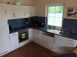 a kitchen with white cabinets and a sink and a window at Dycke Haus 6 in Garz-Rügen
