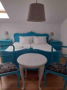 a blue bed with a white table and two blue chairs at Glam One Bedroom Duplex in Vila in city centre in Arad