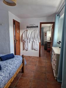 a bedroom with a bed and three dresses hanging on a wall at Casa Araflo in Cortijada Los Chorreros +33 photos