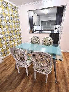 a glass table with four chairs and a kitchen at Casa Dora Gold by SesimbraSunSea in Sesimbra