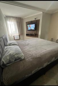 a bedroom with a bed and a flat screen tv at Melhor localização de Floripa. in Florianópolis