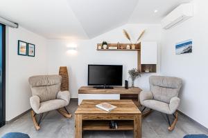 a living room with two chairs and a television at CoralMar Beachfront Apartment -Stunning Ocean Views -Algarve in Armação de Pêra