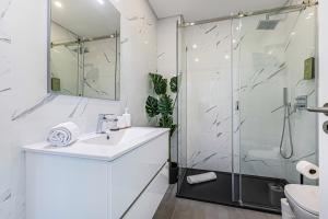 a white bathroom with a shower and a sink at CoralMar Beachfront Apartment -Stunning Ocean Views -Algarve in Armação de Pêra +20 photos