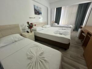 a hotel room with two beds with white sheets at Yıldırım Otel in Didim