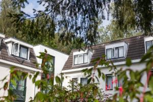 two white houses with white windows and a tree at Witte Berken Natuurhotel in Epe
