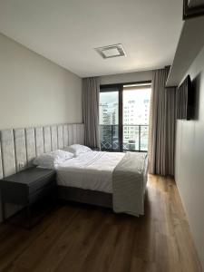 a bedroom with a bed and a large window at Apartamento 100m da Praia Brava - Itajaí in Itajaí