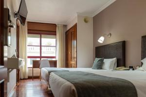 Una habitación de hotel con dos camas y un televisor. en Hotel Alda Centro Pontevedra, en Pontevedra