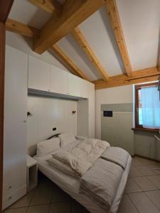 a bed in a room with white walls and wooden ceilings at Casa Ornella in Ledro +104 photos