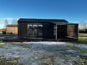 a black tiny house with a black roof at Willa Rauha 1A, minikoti katetulla terassilla, ei saunaa in Lumijoki