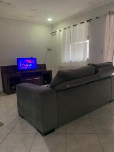 a brown couch in a living room with a tv at Casa in Cabo Frio