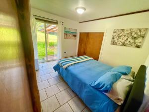ein Schlafzimmer mit einem blauen Bett und einem Fenster in der Unterkunft Driftwood Cottage By The Ocean Beach & Redwoods in Smith River
