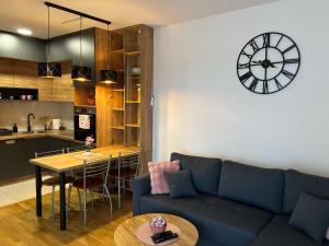 a living room with a couch and a clock on the wall at Apartman NS FREE PARKING in Novi Sad