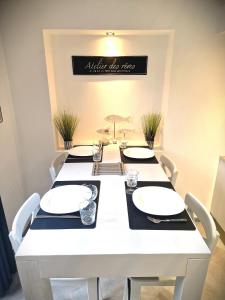 a white dining room table with white plates and chairs at La 34 Tiny House with sunny terrace in Menton