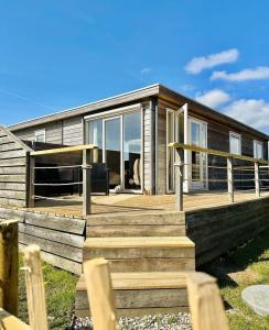a house with a large wooden porch and stairs at Lauwers Loft - 4-persoons chalet aan het water in Anjum