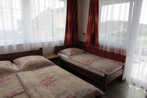 two twin beds in a room with windows at 11 féröhelyes apartman in Balatonlelle