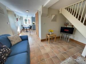 a living room with a blue couch and a staircase at Pretty Cottage In Charming Peaceful Village - Easy Commute to Cambridge - Cambridge Homehost in Cambridge