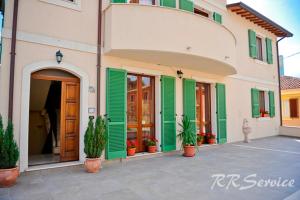 a building with green shutters and potted plants in front of it at Miluna B&B in Nocera Umbra