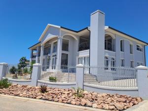 a white house with a fence in front of it at Stone Crown Manor B&B in Mossel Bay