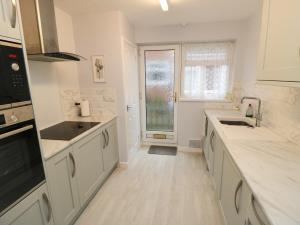 a kitchen with white counters and a sink and a window at Sycamore in Filey