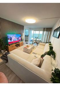 a living room with a large white couch and a television at Koselig leilighet in Stavanger
