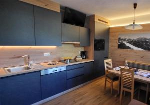 a kitchen with blue cabinets and a table with a dining room at Apartments Dolomie in Ortisei