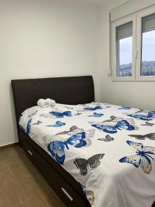 a bed with a blue and white comforter with butterflies on it at Mimura stan in Belgrade