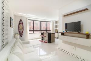 a white living room with a tv and a couch at Apto 1Q c/ Piscina a 650m da Praia PDN0113 in Balneário Camboriú