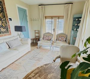 a living room with a white couch and two chairs at De Lindenhof in Tienhoven