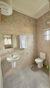 Un baño con un inodoro blanco y un lavabo. en Golden Sands Villa, en Gunjur