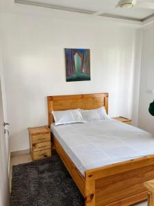 1 cama en un dormitorio con marco de madera en Golden Sands Villa, en Gunjur 4 fotos más