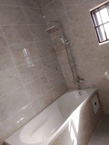 Una bañera blanca en un baño con ventana. en Golden Sands Villa, en Gunjur