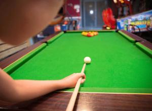 un niño pequeño jugando al billar con una señal en Camping - Piscine - ccb0cfa, en Angles