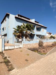 a white house with a palm tree in front of it at Blue Oceano in Santa Maria