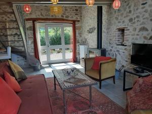 a living room with a couch and a table and a tv at Gîte atypique Nature La Cabane in Vieille-Brioude
