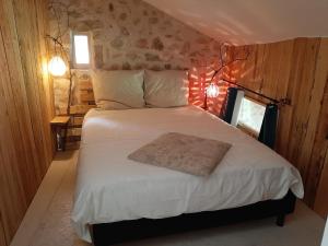 a bedroom with a large bed with white sheets at Gîte atypique Nature La Cabane in Vieille-Brioude
