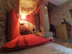um quarto com uma cama vermelha numa parede de pedra em Casa de Campo das Sécias em Vilas Boas