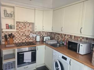 a kitchen with white cabinets and a washer and sink at Spacious two bedroom flat, central location in Plymouth