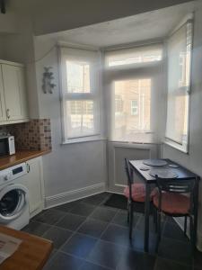 een keuken met een tafel en 2 ramen bij Spacious two bedroom flat, central location in Plymouth